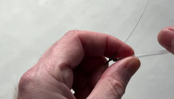 Pass the tag end into the hole and push the whole thing over the top of the swivel.