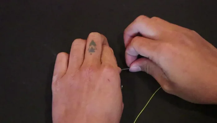 Pinch the line against the hook to hold it in place.