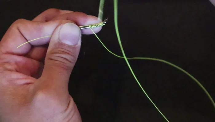 Hold the tag end down against the hook.