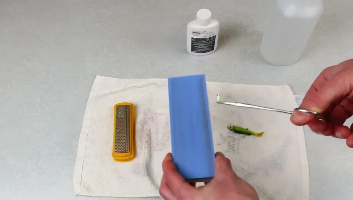 Rub the hook against the sanding block.