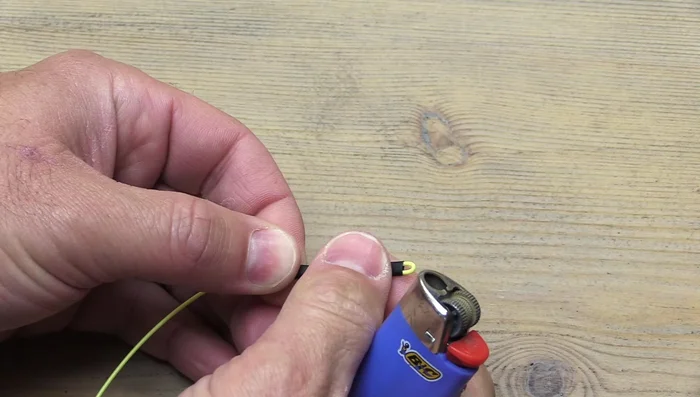 Using a lighter, evenly heat the heat shrink tubing to shrink it around the fly line. Avoid heating the fly line itself at this stage.