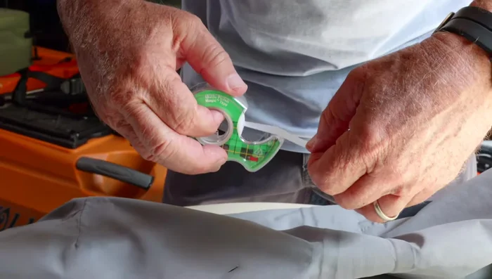 Apply a piece of Scotch tape or duct tape to the back of the tear to prevent Aquaseal bleed-through.