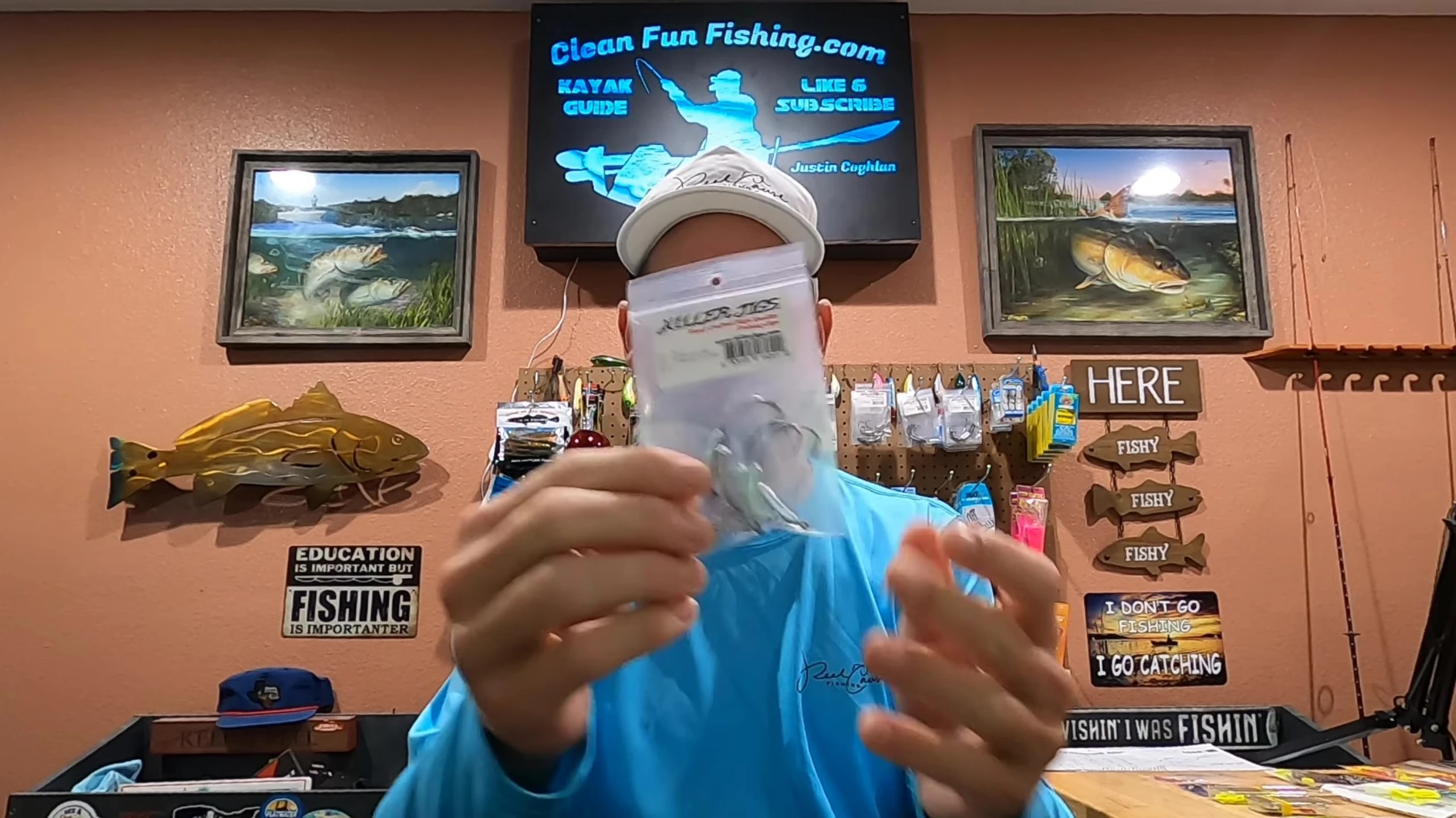 A hand comparing a hook to a soft plastic lure inside its packaging