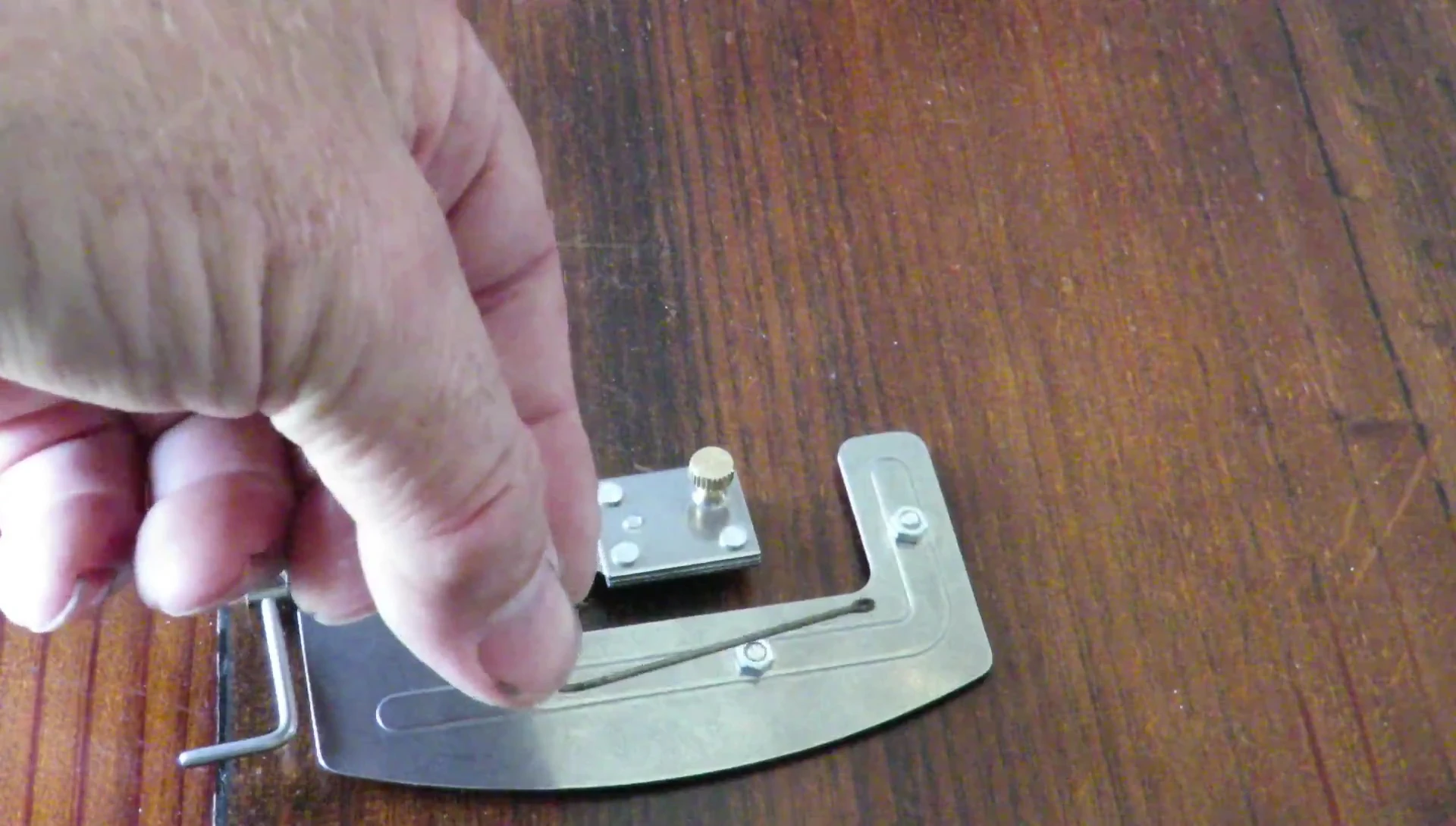 Close-up of the tool, highlighting the thumb screw and slot for the hook.