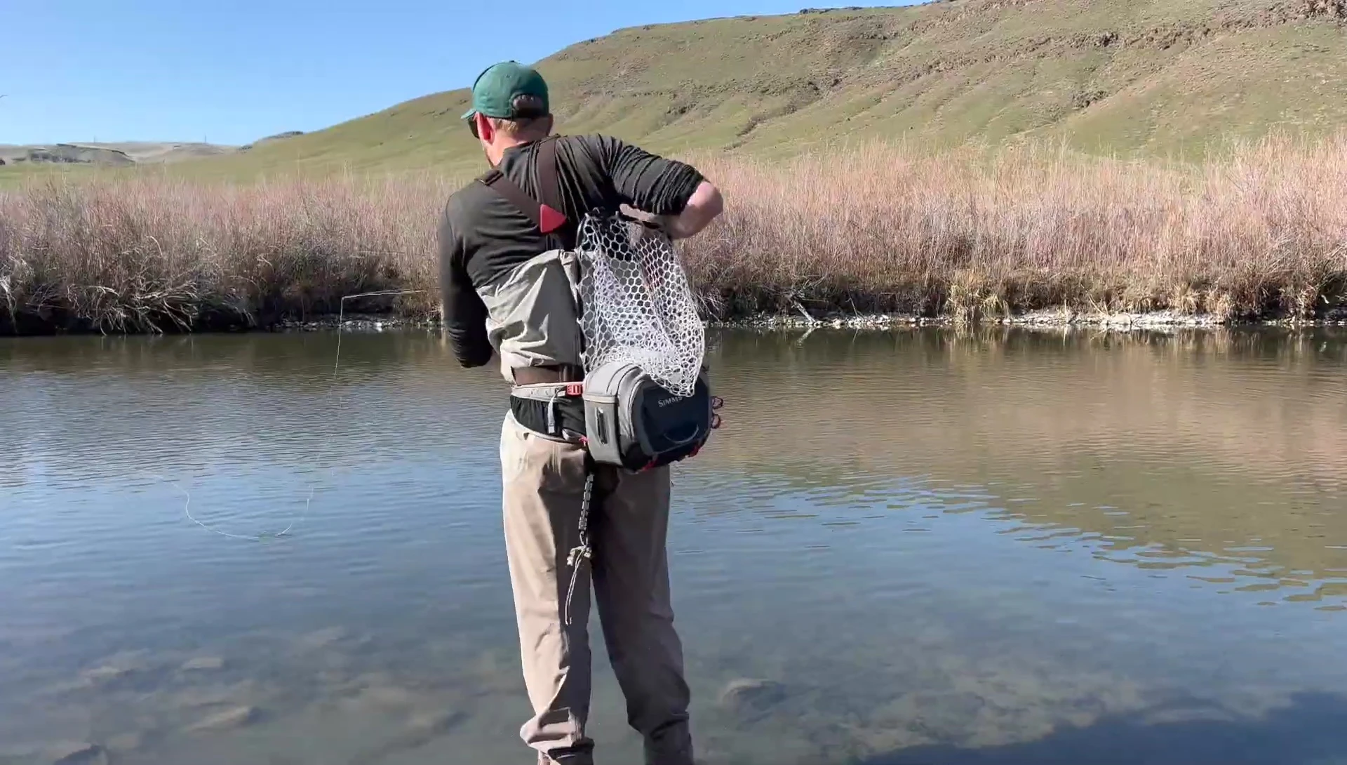 A frustrated angler struggling with a net tangled behind their back