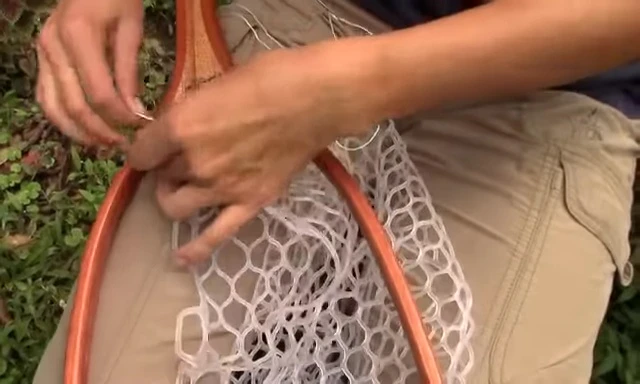 The needle being inserted through the first hole of the wooden frame.