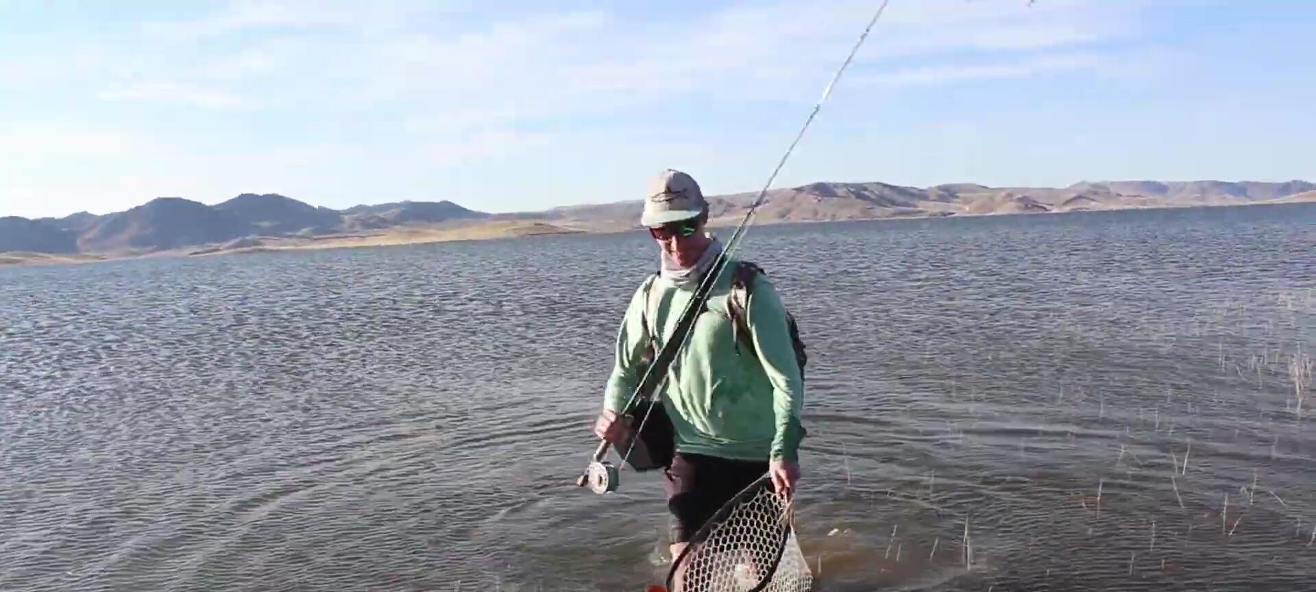 The narrator holding a large fish in the net