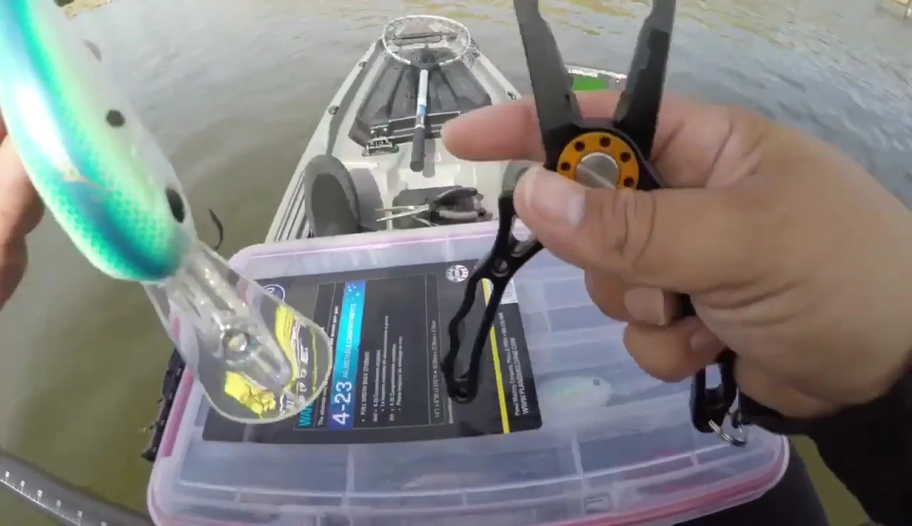 The pliers removing a hook from a crankbait.