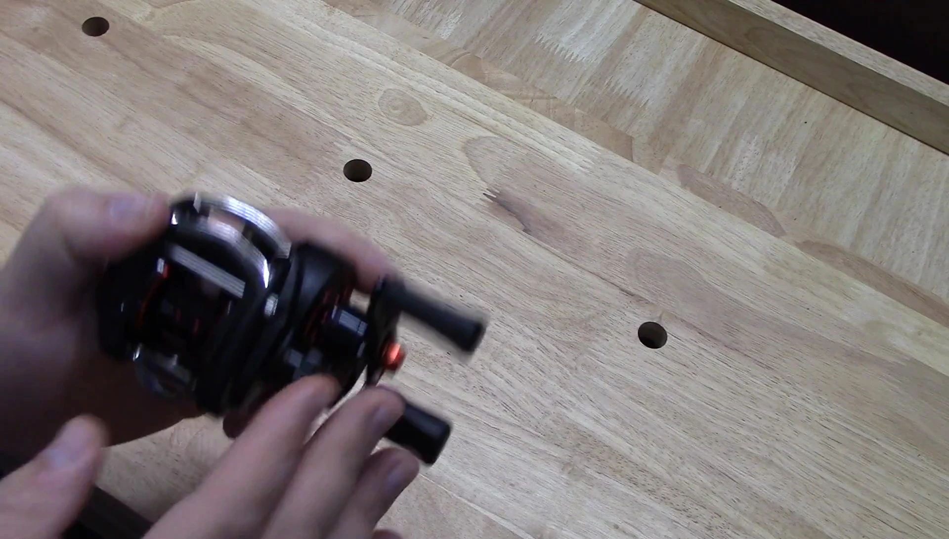Close-up of the reel in the reviewer's hand, showcasing the ergonomics.