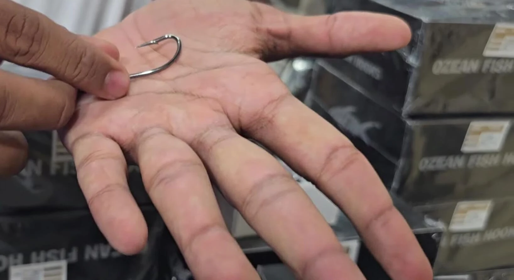 The presenter holding and inspecting an Ozean fish hook.