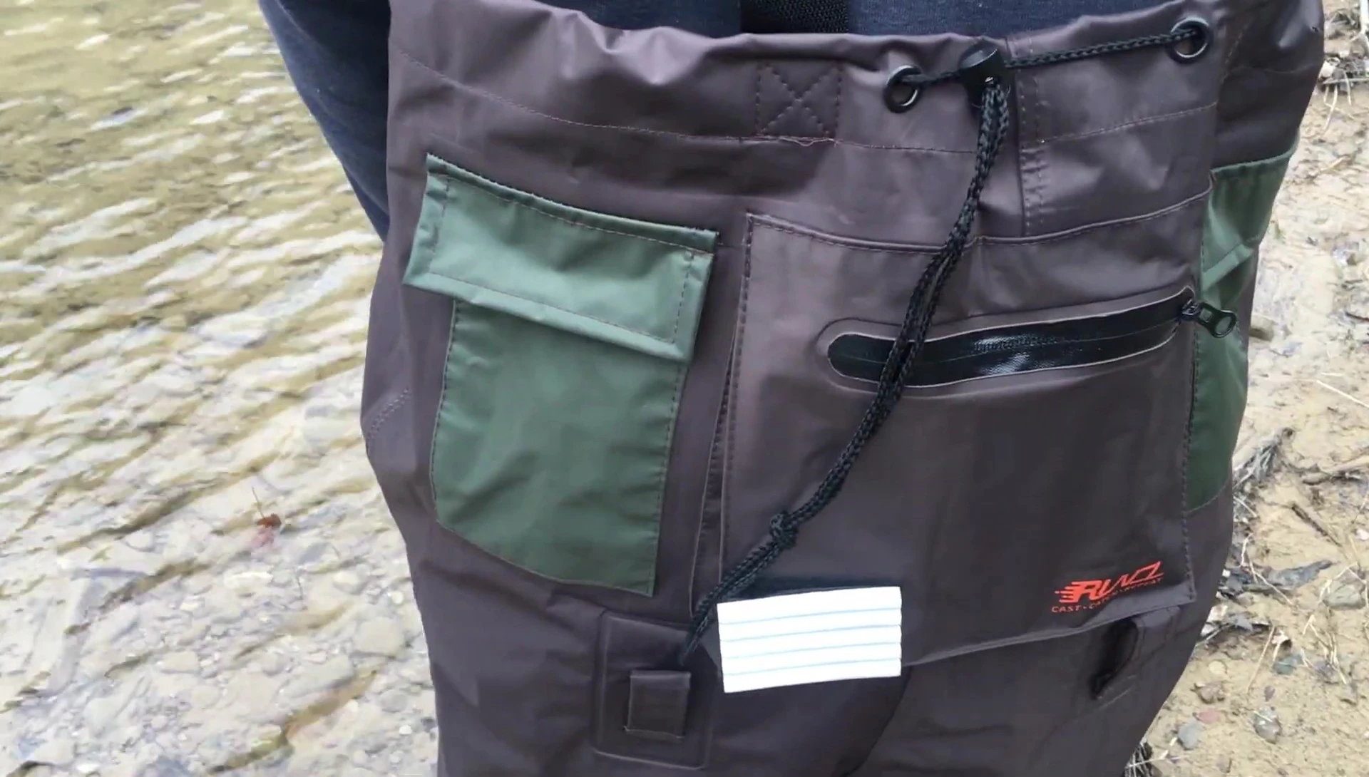 Close-up shot of the person's feet inside the waders in cold water