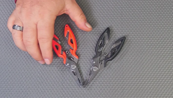 Review of Two-for-One Fishing Pliers: Features a heavy-duty spring, hard plastic handle (orange or black), split ring tool, and integrated cutters.