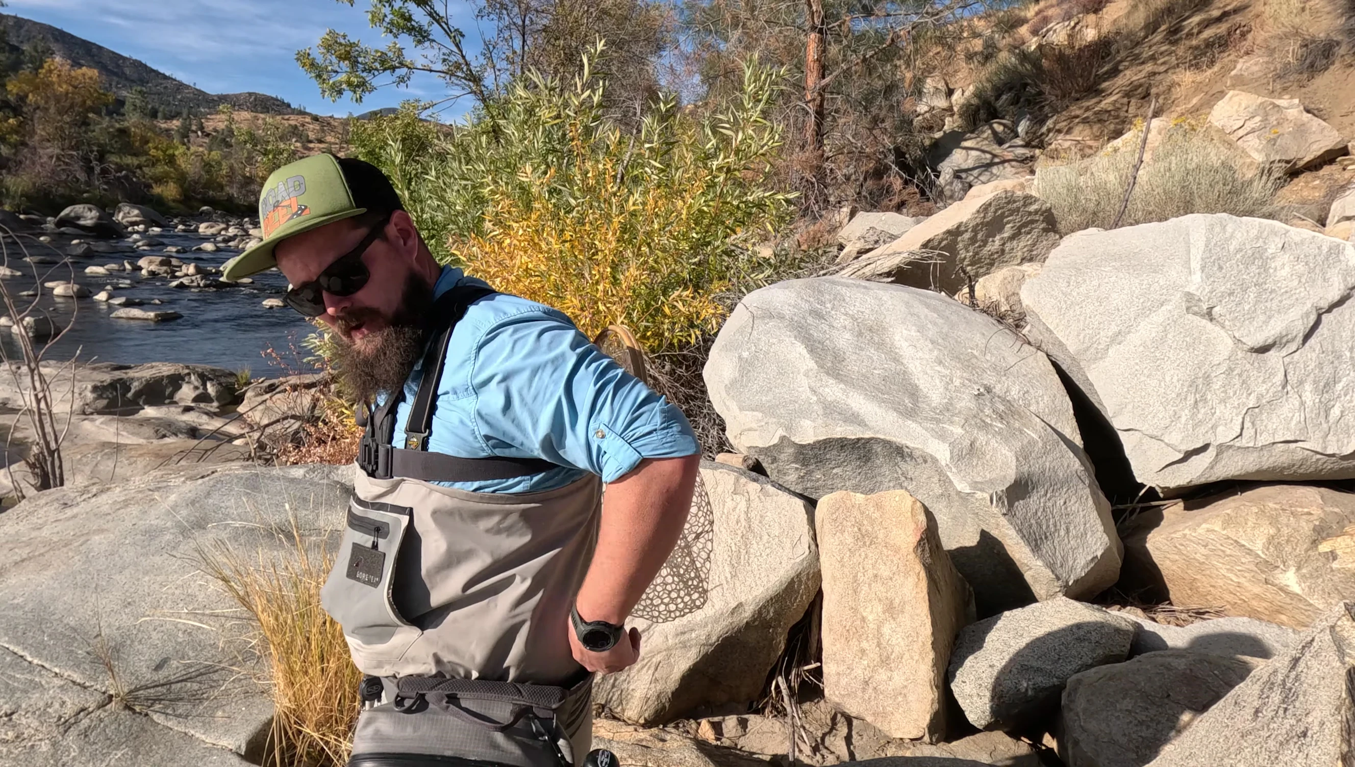 A fly fisherman demonstrating the challenges of carrying a net tucked into his belt.
